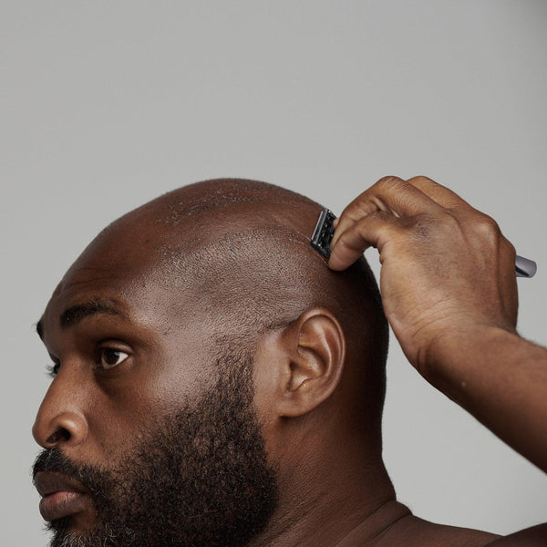 black man shaving his head using frederick benjamin easy primer, best pre shaving primer for black men, best non greasy shaving primer for men of color